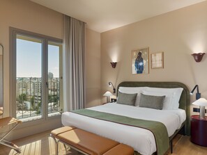 A hotel room with a large bed, a bench, a view of the city, and a cityscape visible through the window. - Leonardo Boutique Hotel Venetian Nicosia (Nicosia)