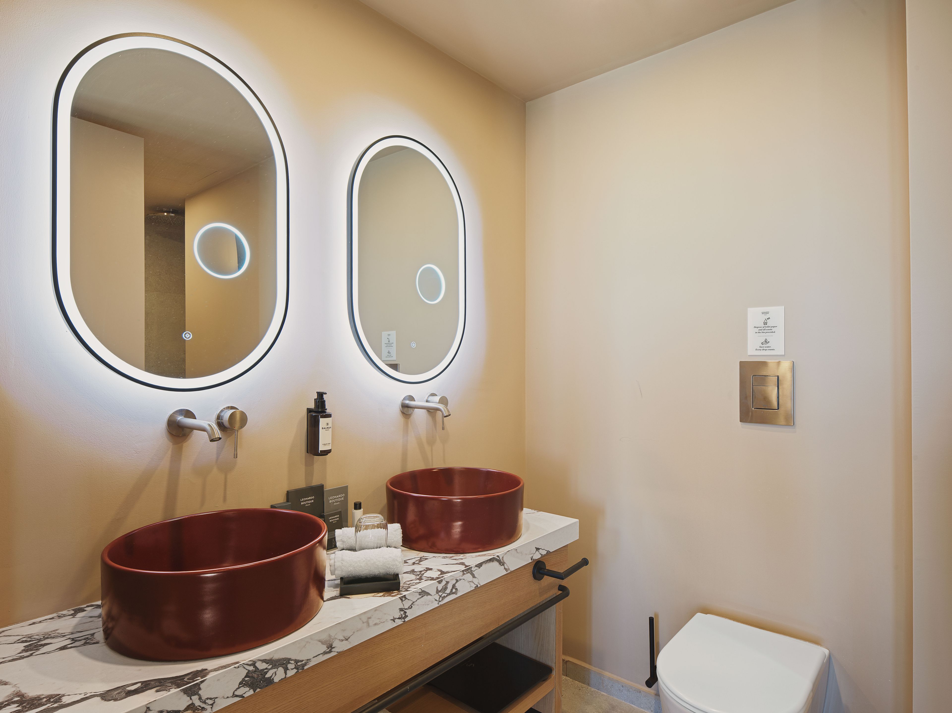 Un baño con dos lavamanos, un espejo y un inodoro.