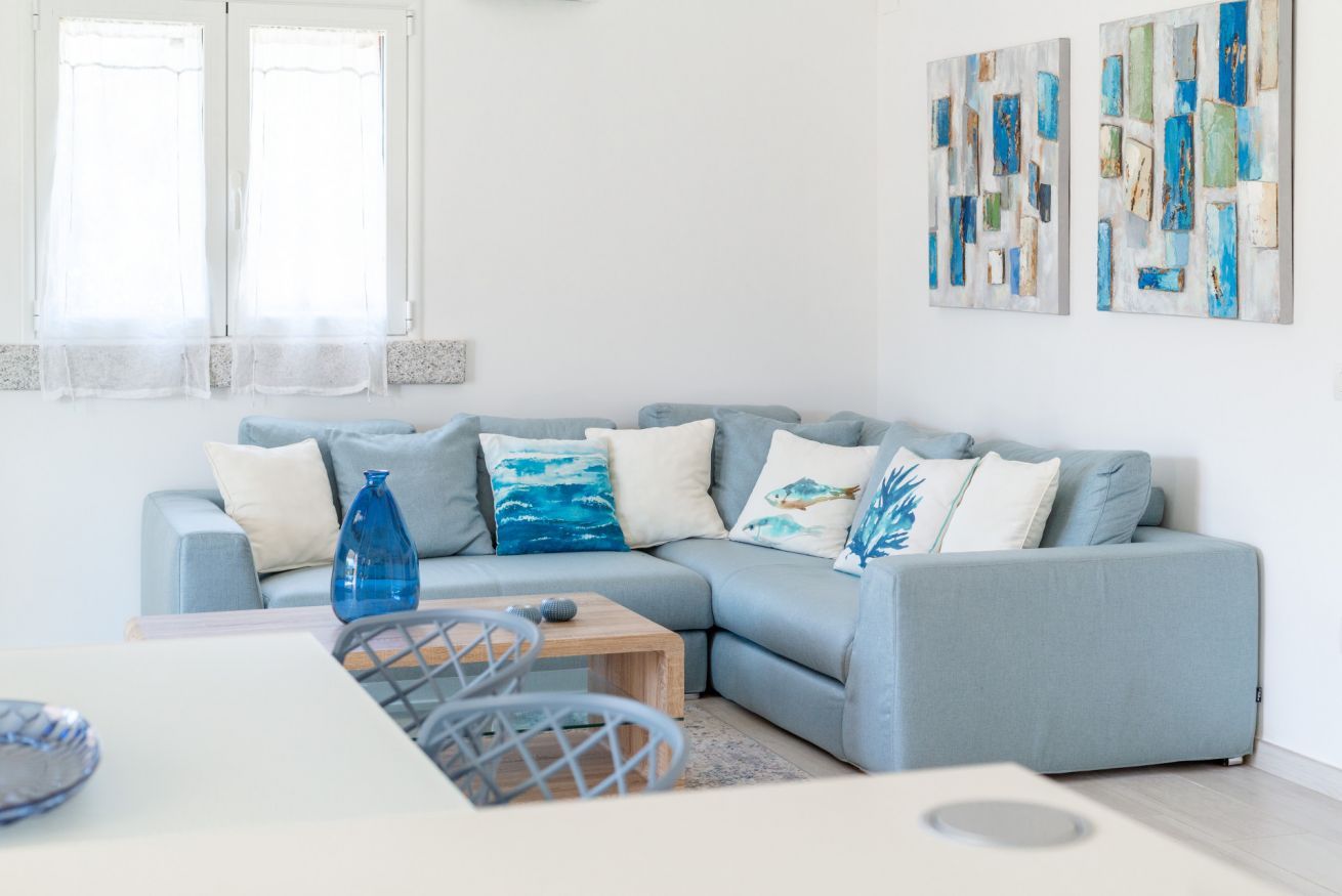 A modern living room with a light blue sofa, a coffee table, and two abstract paintings on the wall.