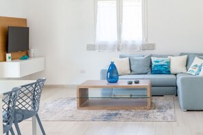 Un saló modern amb un sofà, una taula de centre, un televisor i una cadira.