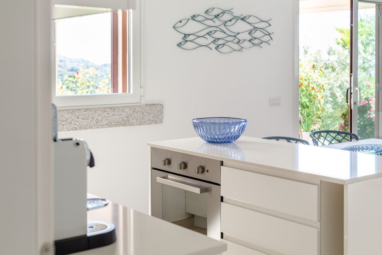 A modern kitchen with a white countertop, a blue glass bowl, and a fish wall art piece.