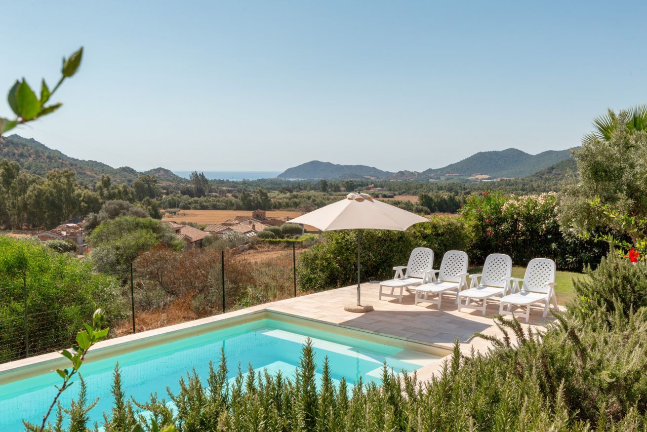 A swimming pool with lounge chairs and a view of the countryside.
