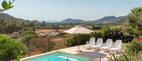 Una piscina con sillones de descanso y vistas al campo.