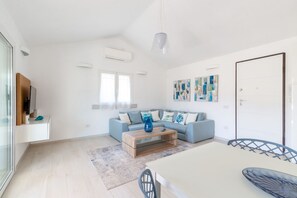 Ein modernes Wohnzimmer mit einer Couch, einem Couchtisch und einem Essbereich mit Tisch und Stühlen.
