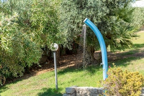 Ein Garten mit einem Wasserspiel, darunter eine geschwungene, blaue Struktur und ein weißer, kugelförmiger Gegenstand.