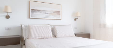 Ein Schlafzimmer mit einem Bett, zwei Nachttischen, einer Wandleuchte und einem gerahmten Kunstwerk.