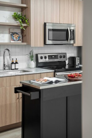 Eine moderne Küche mit Edelstahlgeräten, Holzschränken und einer Arbeitsplatte aus Granit.