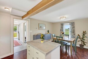 A kitchen with a dining area, wooden ceiling beams, and a view of the outdoors.