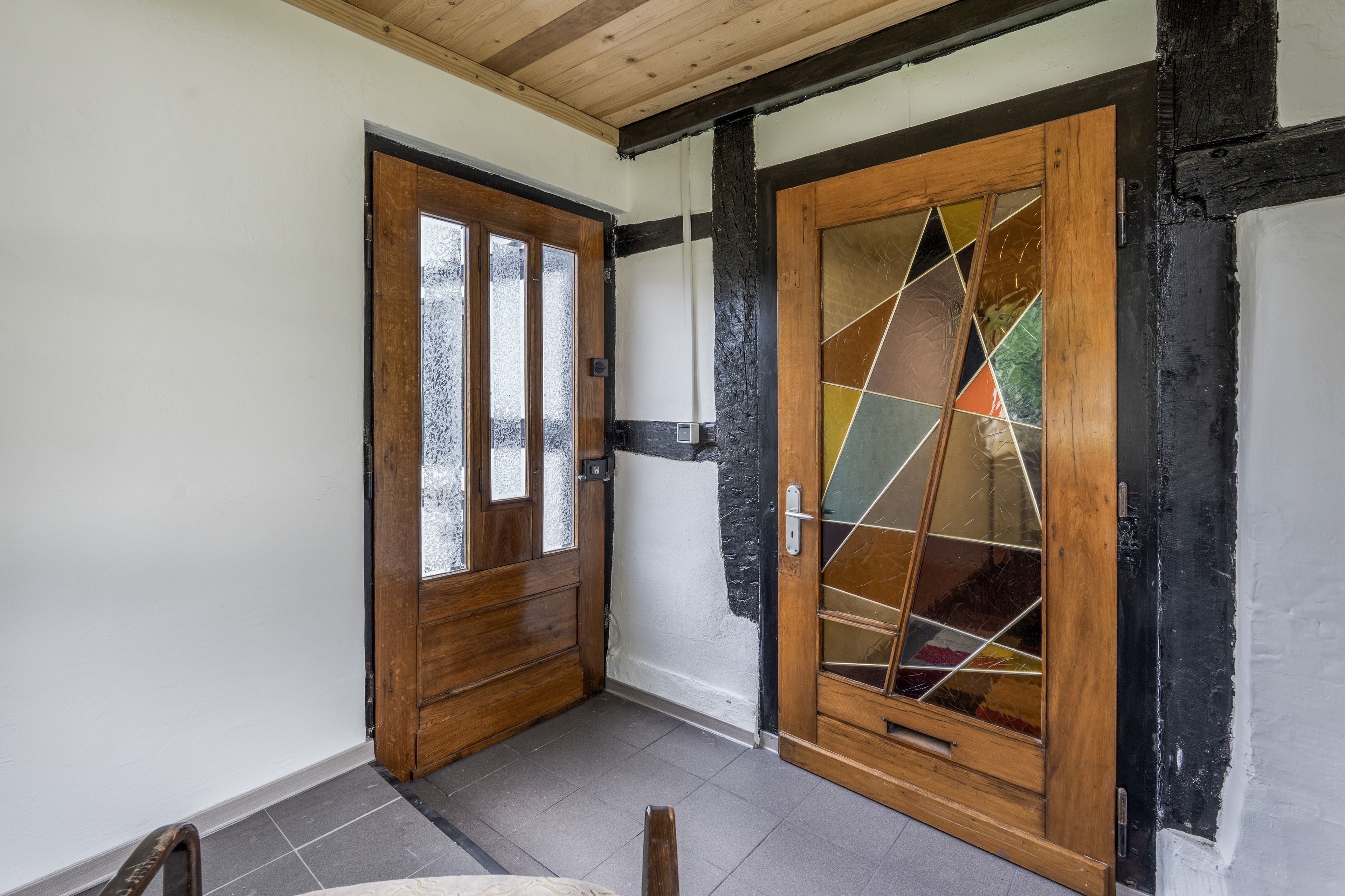 Ein Zimmer mit einer Holztür und einer großen Glastür mit geometrischem Muster.
