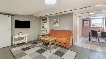Un salon avec un canapé, une table basse, un téléviseur, une bibliothèque et un tableau accroché au mur.