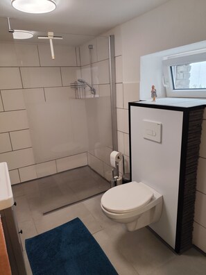Ein modernes Badezimmer mit Dusche, Toilette und einem kleinen Fenster über dem Waschbecken.