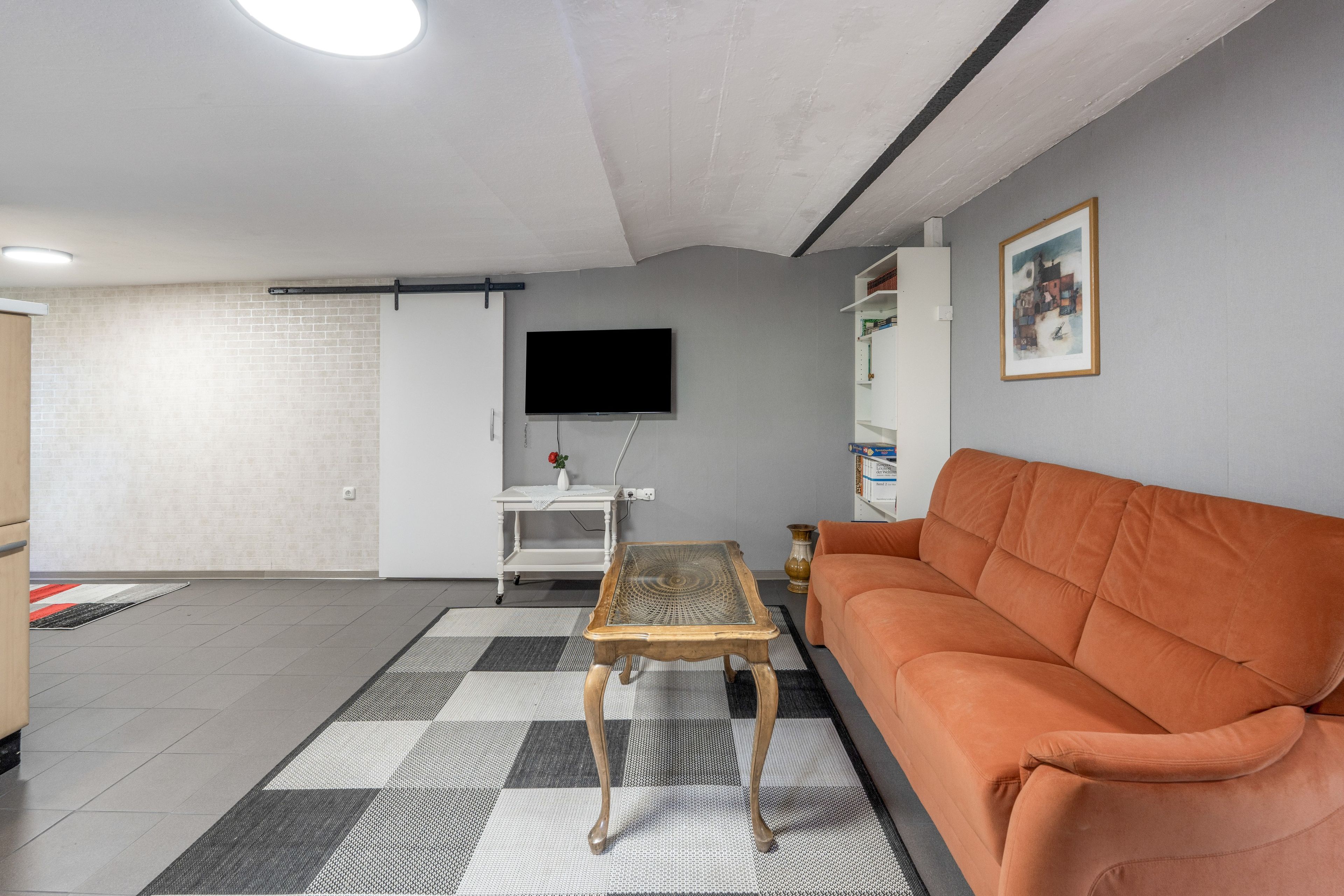 Ein Wohnzimmer mit einer Couch, einem Couchtisch, einem Fernseher und einem Bücherregal.