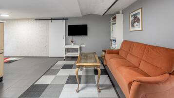 Ein Wohnzimmer mit einer Couch, einem Couchtisch, einem Fernseher und einem Bücherregal.