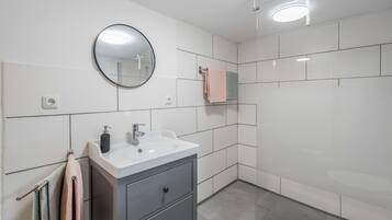 Une salle de bain moderne avec un lavabo blanc, un miroir et un porte-serviettes.