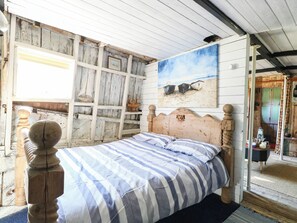 A room with a wooden bed, a painting of boats on the wall, and a rustic wooden ceiling. - Ladies of Bolton (Norwich)