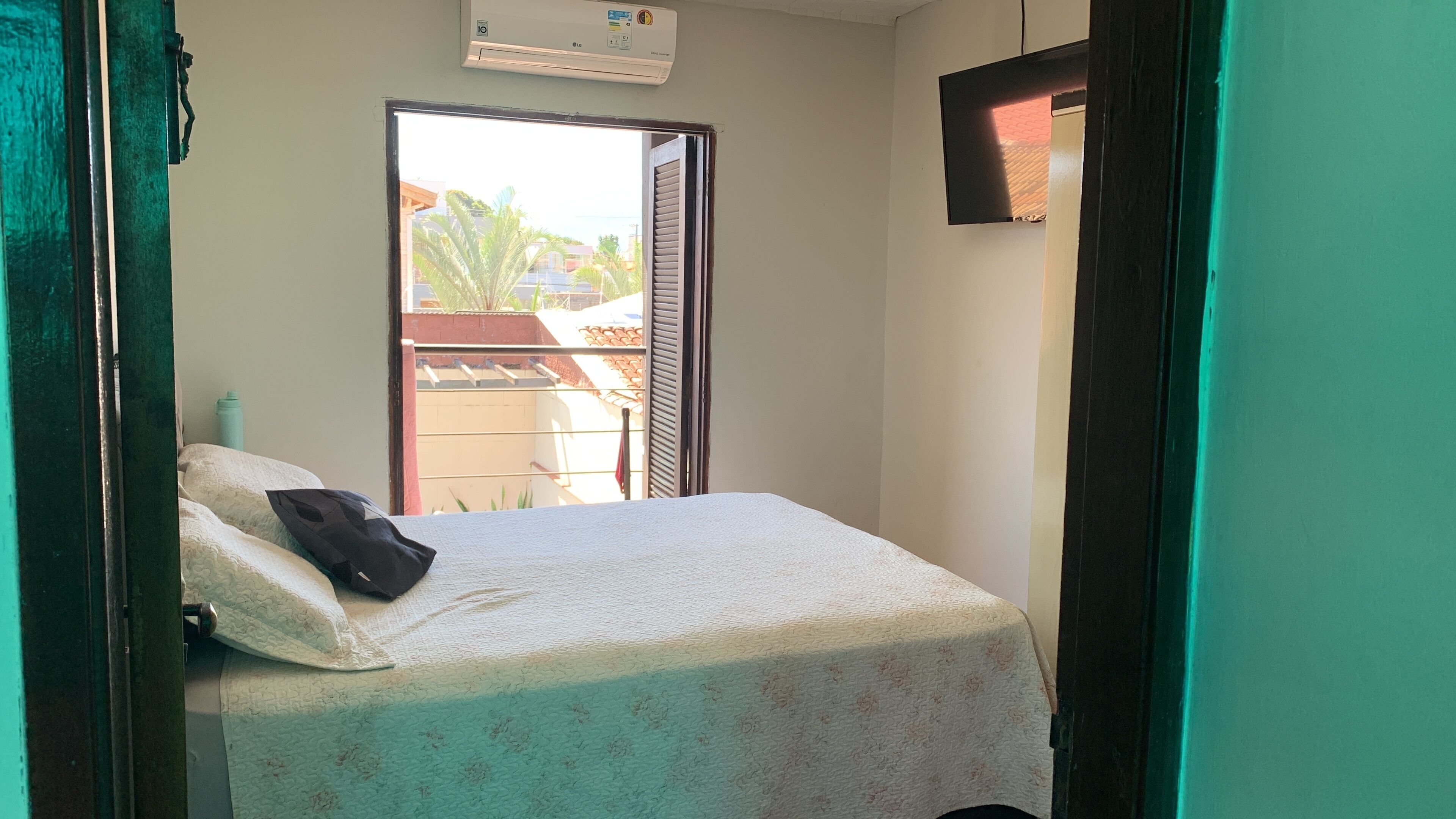 Ein Zimmer mit einem Bett, einem Fenster und einer Klimaanlage.