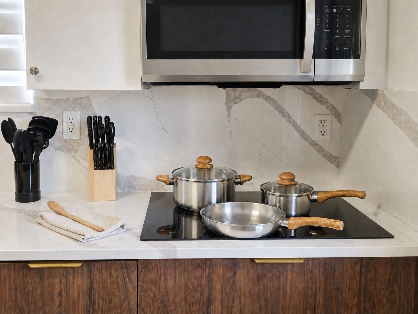 A kitchen with a microwave, stove, pots, and utensils.