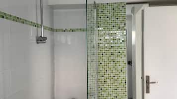 A bathroom with a glass shower enclosure, a bathtub, and a white door.