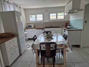 A compact kitchen with a dining table, chairs, a microwave, and a sink. - Apartment 'One-story  with Garden' (Étampes)