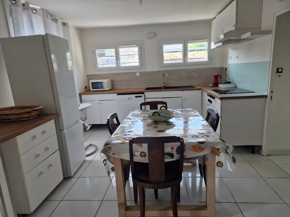 A compact kitchen with a dining table, chairs, a microwave, and a sink.