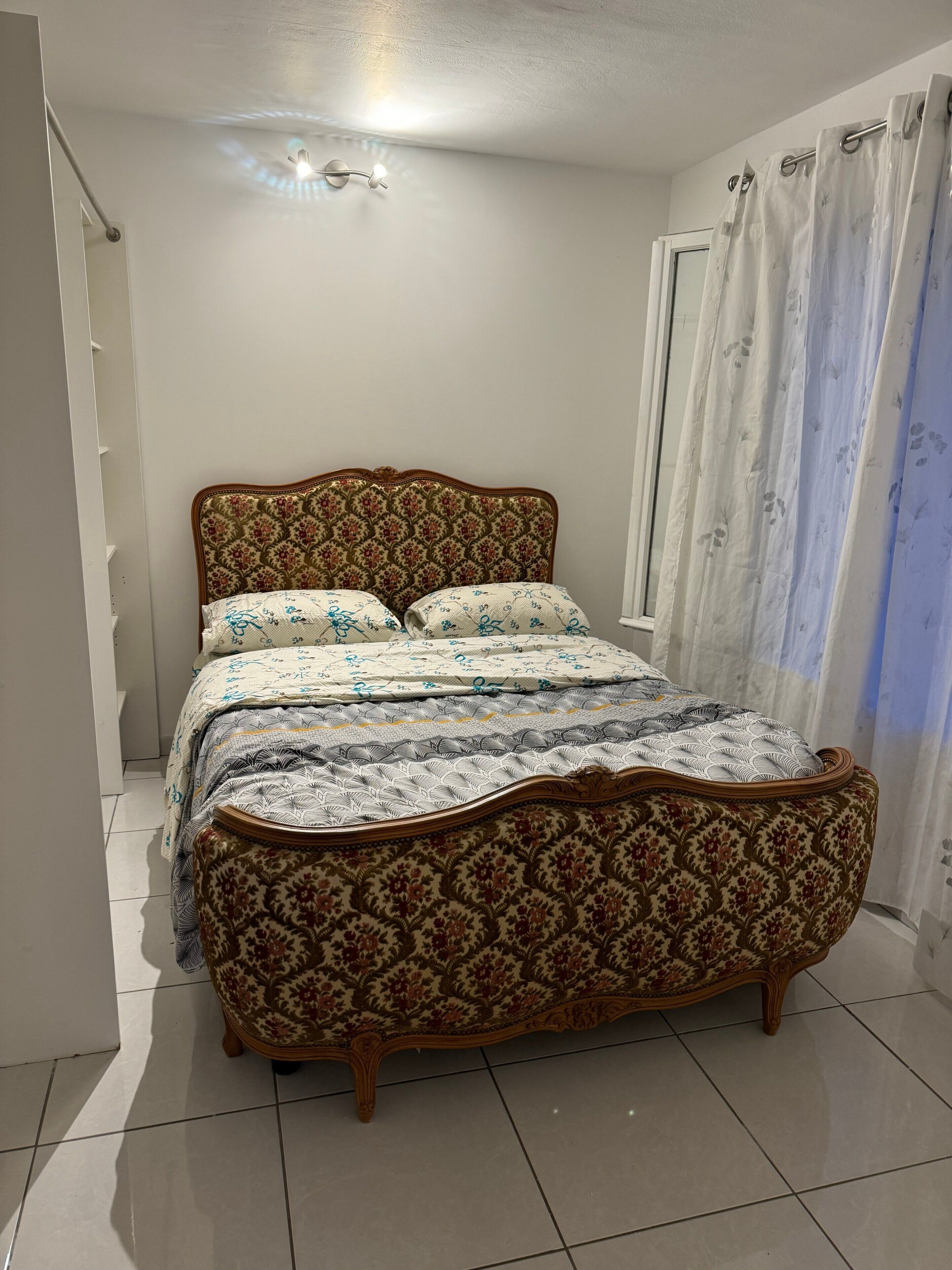 A bedroom with a bed, a window with curtains, and a ceiling light.