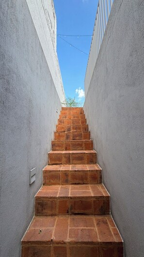 Eine enge Wendeltreppe mit Backsteinmuster, die nach oben führt, begrenzt von schlichten Wänden.