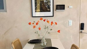 Et spiseområde med et hvidt bord, stribet dug og en vase med orange blomster.