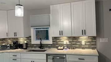 A modern kitchen with white cabinets, a stainless steel refrigerator, and a tiled backsplash.