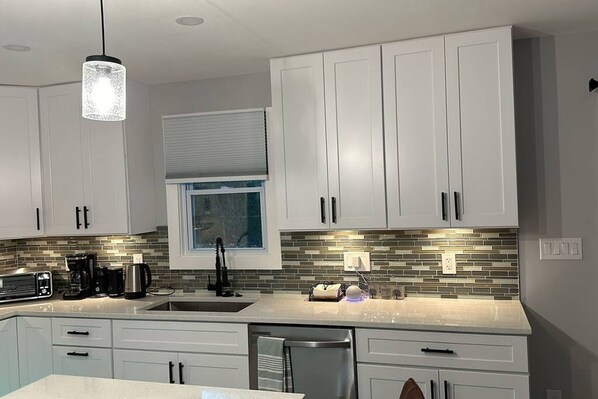 A modern kitchen with white cabinets, a stainless steel refrigerator, and a tiled backsplash. - Urban Xcape- Family Vibe With Plush Amenities (Silver Spring)