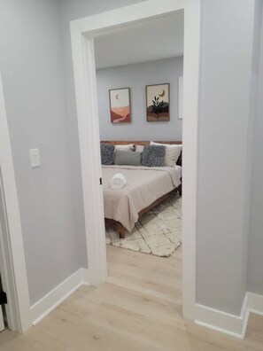 Un dormitorio con cama, mesita de noche y una obra de arte en la pared.