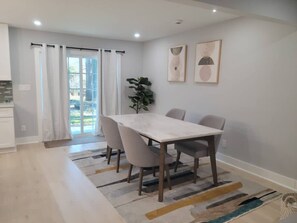 A modern dining area with a table and chairs, a plant, and artwork on the wall. - Urban Xcape- Family Vibe With Plush Amenities (Silver Spring)