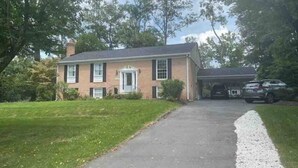 A two-story house with a front porch, a garage, and a driveway leading to the entrance. - Lux Family Xcape With Hottub Fireplace Deck BBQ (Silver Spring)