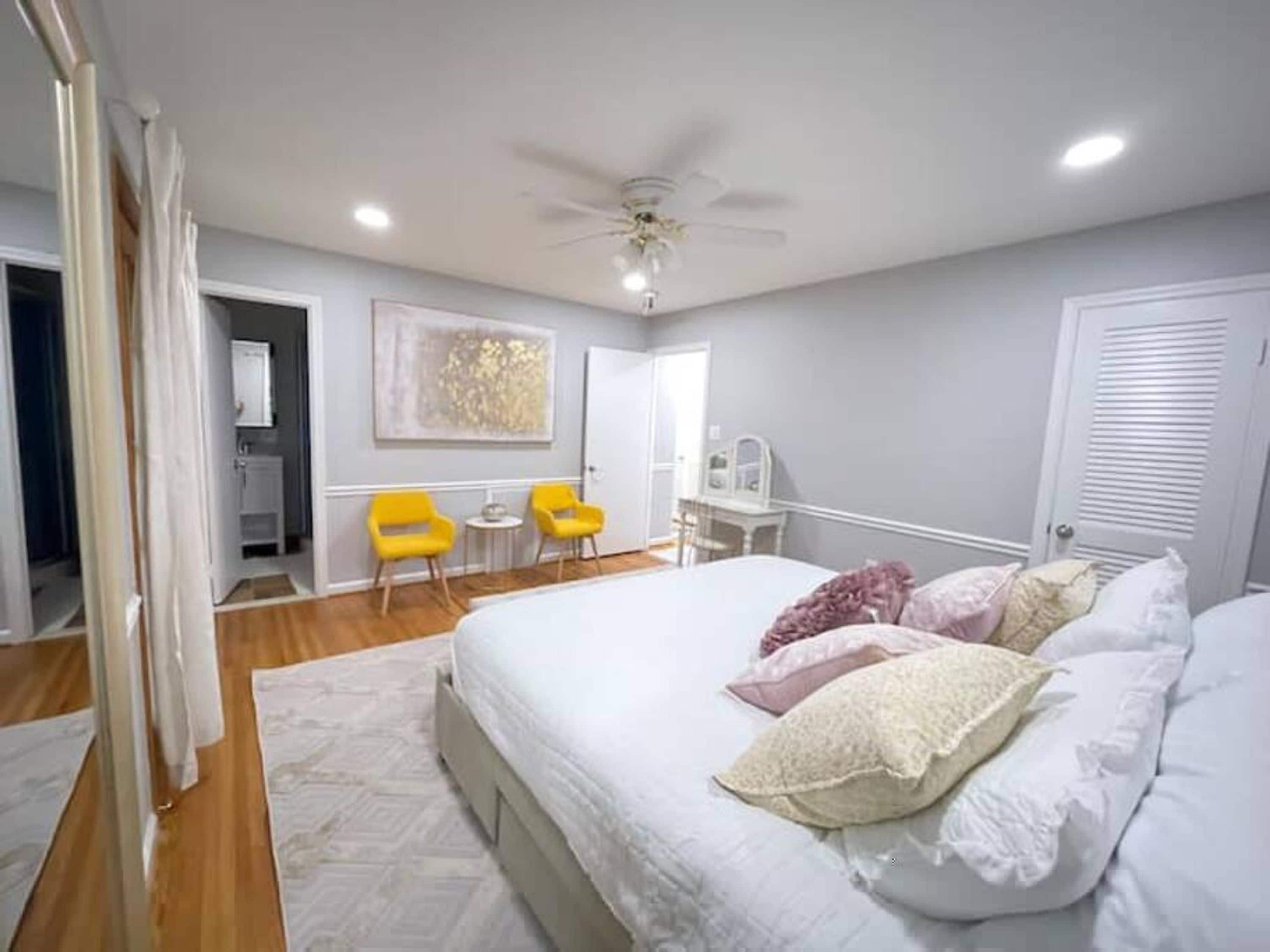 A bedroom with a bed, a ceiling fan, and a small table with chairs.