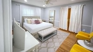 A bedroom with a bed, a bedside table, a chair, a ceiling fan, and a window with curtains. - Lux Family Xcape With Hottub Fireplace Deck BBQ (Silver Spring)