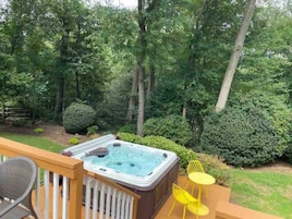 Un jacuzzi en una terraza con vistas a un área boscosa.