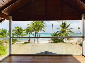 Um deck de madeira com vista para uma praia e palmeiras.