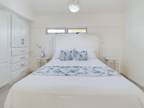 Quarto com cama, duas mesas de cabeceira, guarda-roupa e janela com persianas.