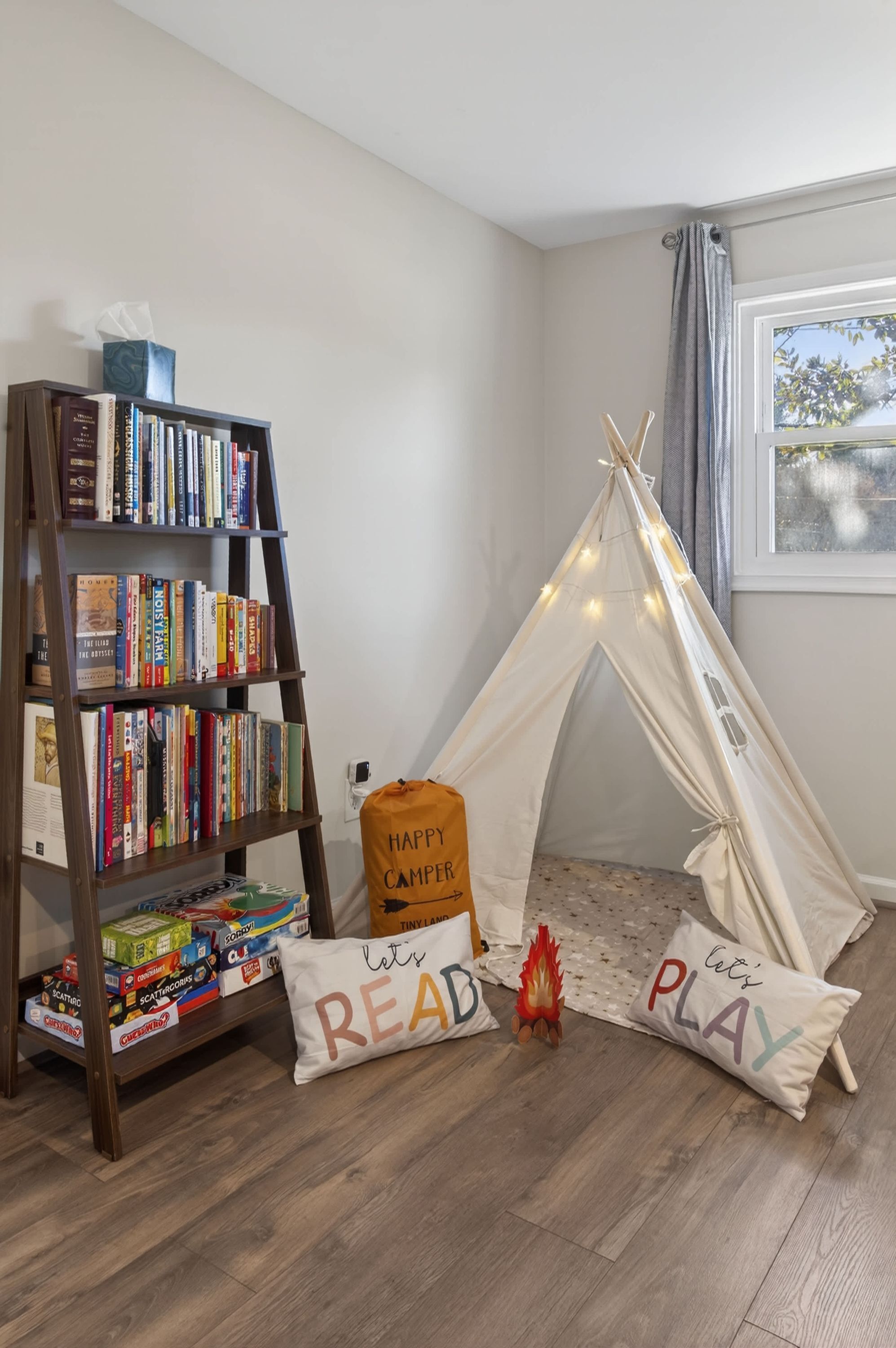 Una habitación con una estantería, una tienda de campaña y dos almohadas con texto.