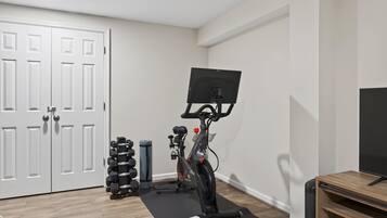A home gym with a stationary bike, dumbbells, and a yoga mat.