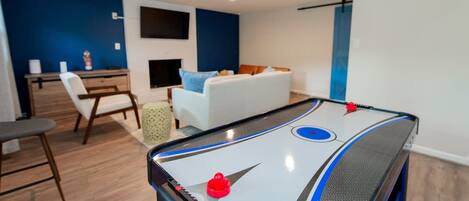 Une pièce équipée d’une table de billard, d’un canapé, d’une table basse et d’un téléviseur fixé au mur.