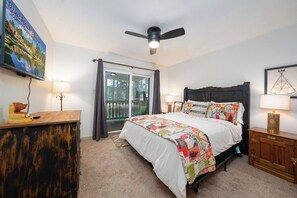 Ein Schlafzimmer mit einem Bett, einem Deckenventilator, einer Schiebetür aus Glas und einem Bild an der Wand.