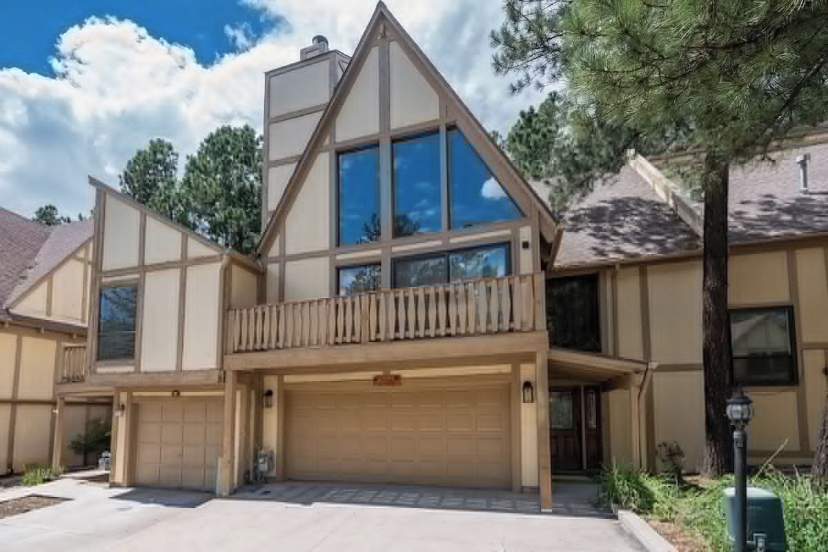 A two-story house with a large garage, a balcony, and a well-maintained lawn.