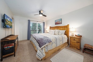 A bedroom with a bed, a ceiling fan, a nightstand, a TV, and a window with curtains. - Innsbrook Vacation Townhome 23 (Ruidoso)
