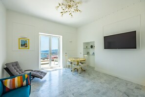 Ein geräumiges Wohnzimmer mit Balkon, Essbereich und flachbildfernseher an der Wand.