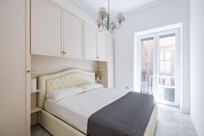 Ein Schlafzimmer mit einem Bett, einer Kristallleuchter und Blick nach draußen.