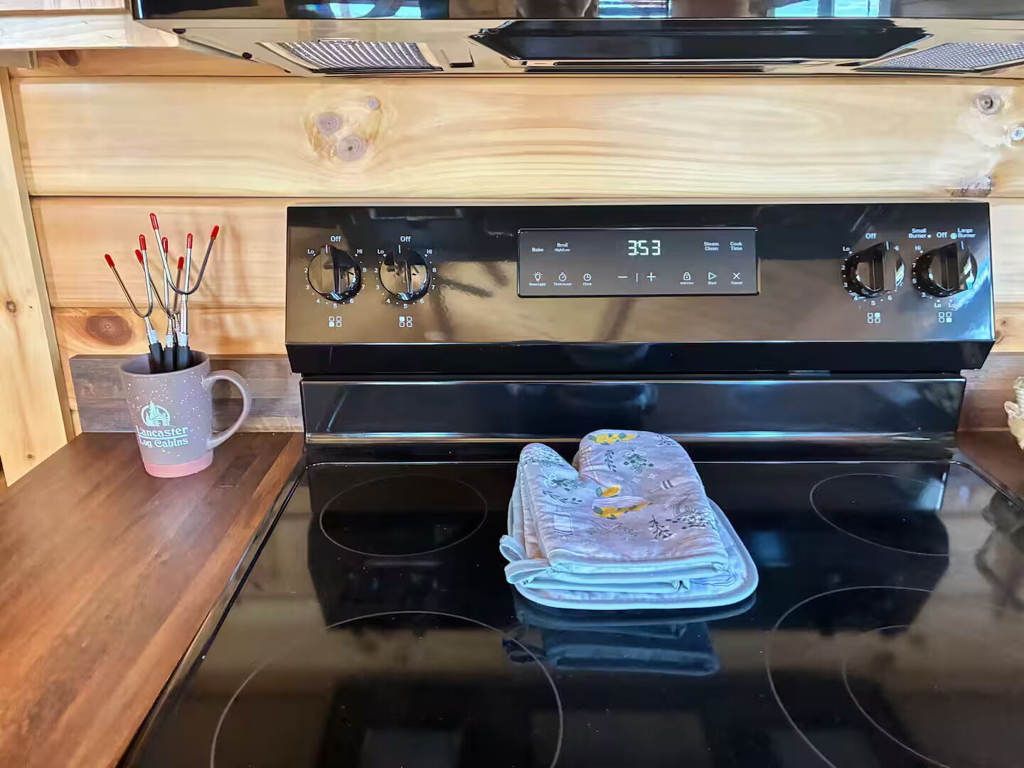 Una cocina con estufa, horno y una taza con pinceles.