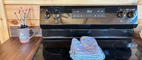 Una cocina con estufa, horno y una taza con pinceles.