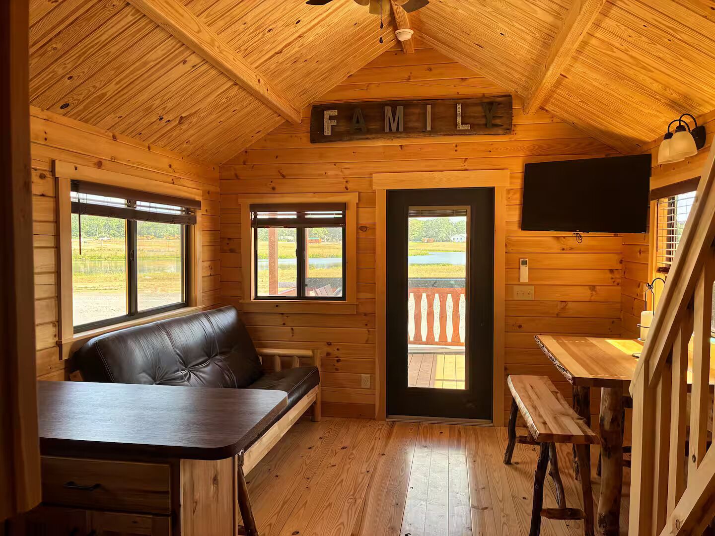 A cozy cabin interior with a wooden ceiling, a leather couch, a dining table, and a sign that reads 'FAMILY'.