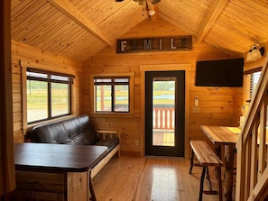 Een gezellig cabin interieur met een houten plafond, een leren bank, een eettafel en een bordje met de tekst 'FAMILIE'.