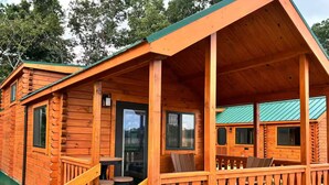 A wooden cabin with a porch, a staircase, and a table with chairs.
